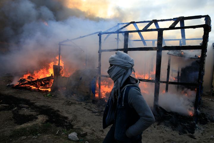 A migrant walks past a burning shelter in the Jungle refugee camp on Feb. 29, 2016. France agreed to take in 30,000 Syrian refugees over a period of two years. Meanwhile, thousands of refugees from other countries, like Iraq and Afghanistan, have been living in the Jungle in Calais and a camp near Dunkirk.