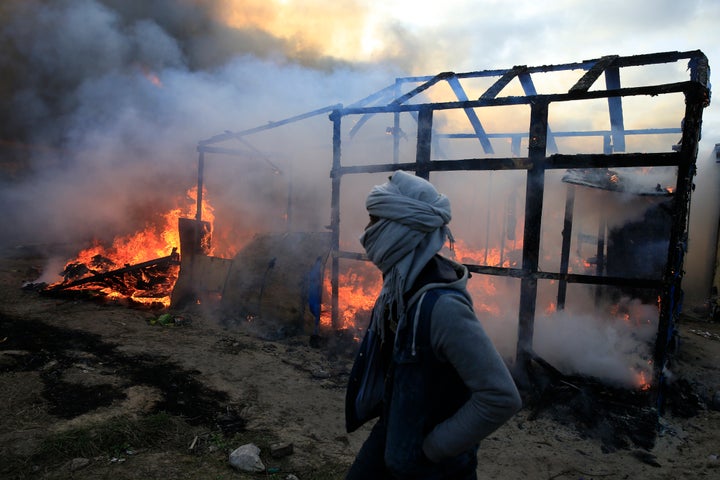 A migrant walks past a burning shelter in the Jungle refugee camp on Feb. 29, 2016. France agreed to take in 30,000 Syrian refugees over a period of two years. Meanwhile, thousands of refugees from other countries, like Iraq and Afghanistan, have been living in the Jungle in Calais and a camp near Dunkirk.