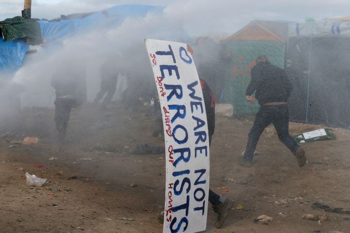 A sign in the Jungle refugee camp that reads, "We Are Not Terrorists - So Don't Destroy Our Homes." Because the U.K. is not among the E.U. countries allowing free movement across borders, refugees and migrants cannot legally enter. Many die while attempting the perilous journey by jumping onto moving trains and trucks.