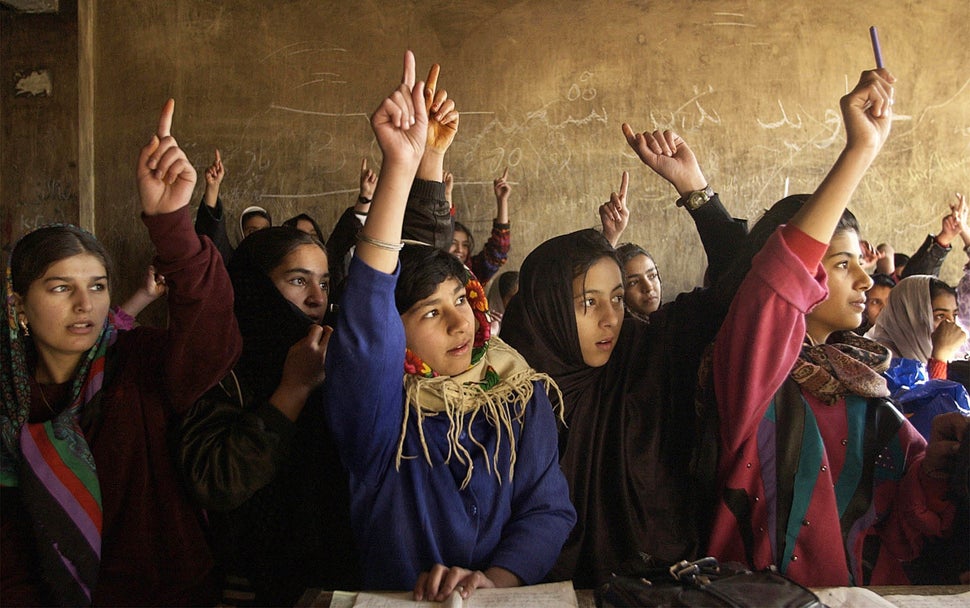 Afghani girls raise their hands to answer a question in math class. 