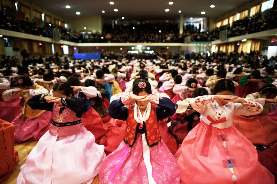 Students wearing traditional hanbok dresses bow as they attend a graduation and coming-of-age ceremony at the Dongmyeong girl