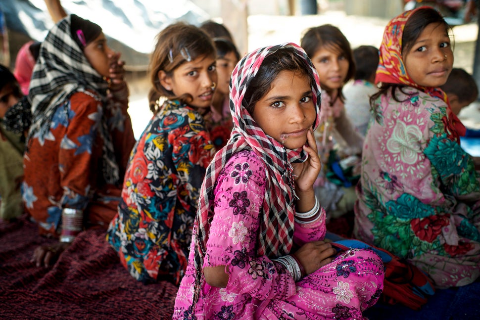 Children sit on the ground with a temporary roof to protect them against the strong sun in a small village called Bilwadi in 