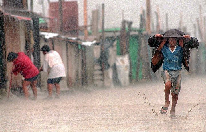 A child shields himself from the rain during an extreme El Niño event in Lima, Peru. Health authorities reported that the flooding caused by the meteorological phenomenon exacerbated poor sanitary conditions, provoking outbreaks of cholera, malaria, dysentery and conjunctivitis.