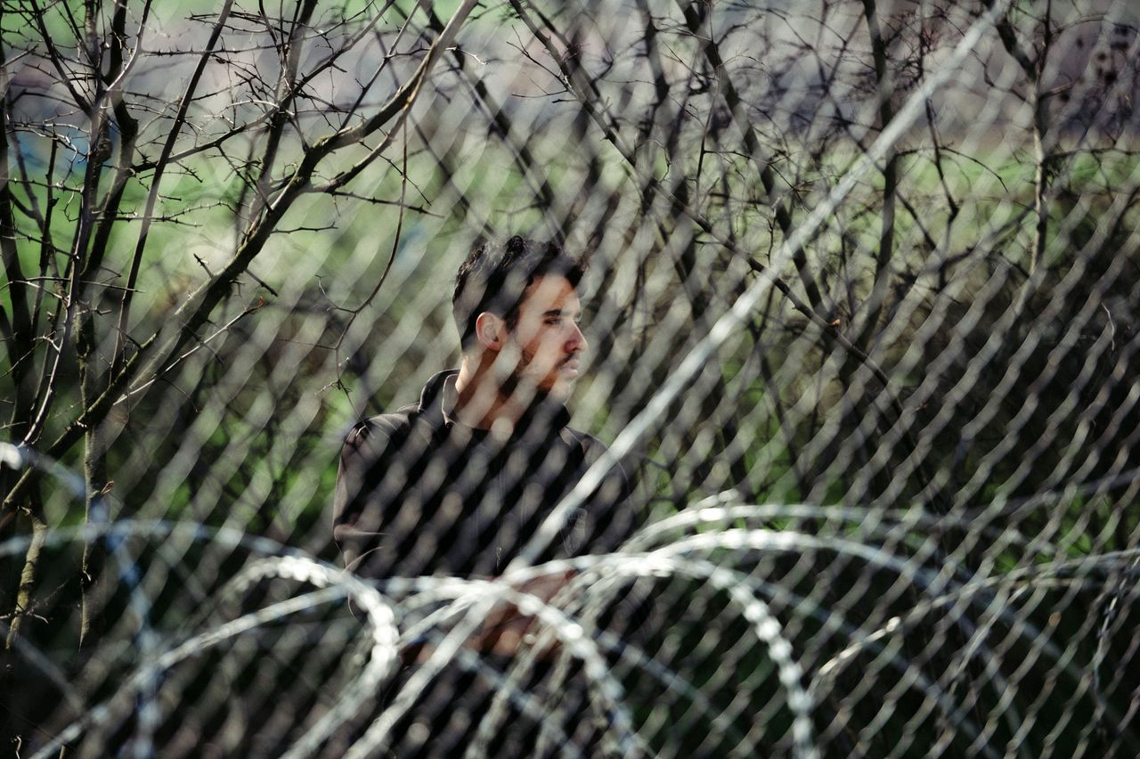 A man stands behind a fence near the Greece-Macedonia border. Some 30,000 migrants and refugees are currently stranded in Greece -- up to 12,000 of them at the border.