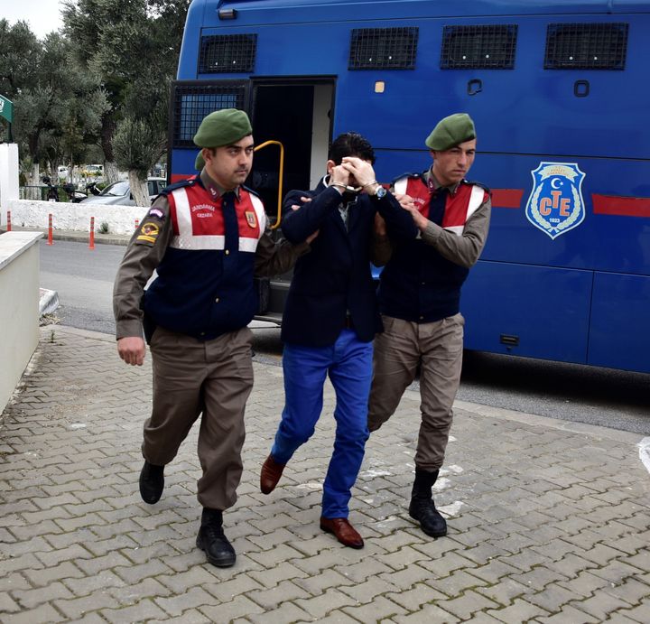 Turkish gendarmeries escort a Syrian arrested on suspicion of causing the deaths of 5 refugees, including Aylan Kurdi.