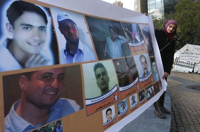 A woman holds a banner showing portraits of Syrian citizens held prisoner in Syrian jails, during a sit-in at the U.N. headqu