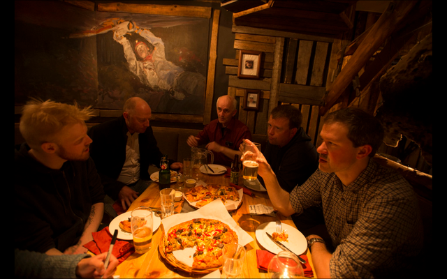 Sveinung Thesen (right, front) and choir members enjoy pizza and beer after the show.