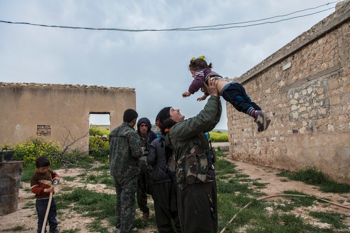 Sarah, a member of YPJ, spends some time with a little girl of a family she is visiting on her way from one village to another in Western frontline near the city of Kobane on April 9, 2015. The city of Kobane is liberated though the fight in the frontlines around it is still goes on.