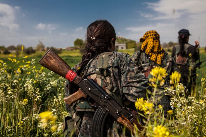 Three fighters from the YPJ (Women's Protection Units), walk through the flower fields in Western frontline near the city of Kobane on April 7, 2015. The city of Kobane is liberated though the fight in the frontlines around it is still goes on.