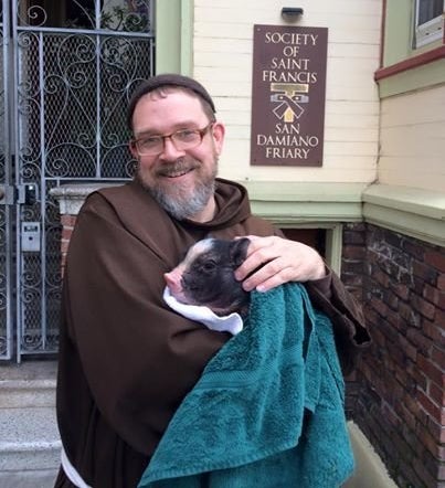 Brother Damien Joseph is seen cradling the piglet, shortly after its capture Tuesday morning.