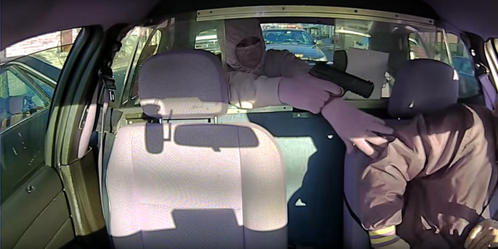 A taxi driver is seen being taken by surprise when his passenger pulls a gun on him, not realizing a sheriff's deputy is park