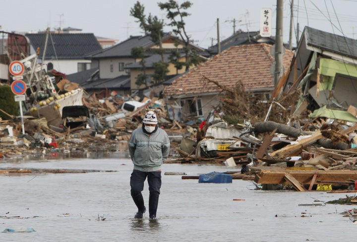 A man looks for the remains of his house, which was destroyed by the tsunami, at Watari town in Miyagi prefecture on March 14