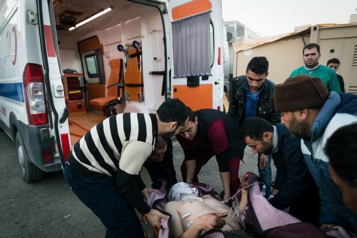 A victim of a barrel bomb attack in Aleppo is helped into a Turkish ambulance on call at the Bab al Salama Hospital near the Turkish border. The hospital is a key point of transfer for the seriously injured between war-torn Syria and the better equipped state hospitals in Turkey.