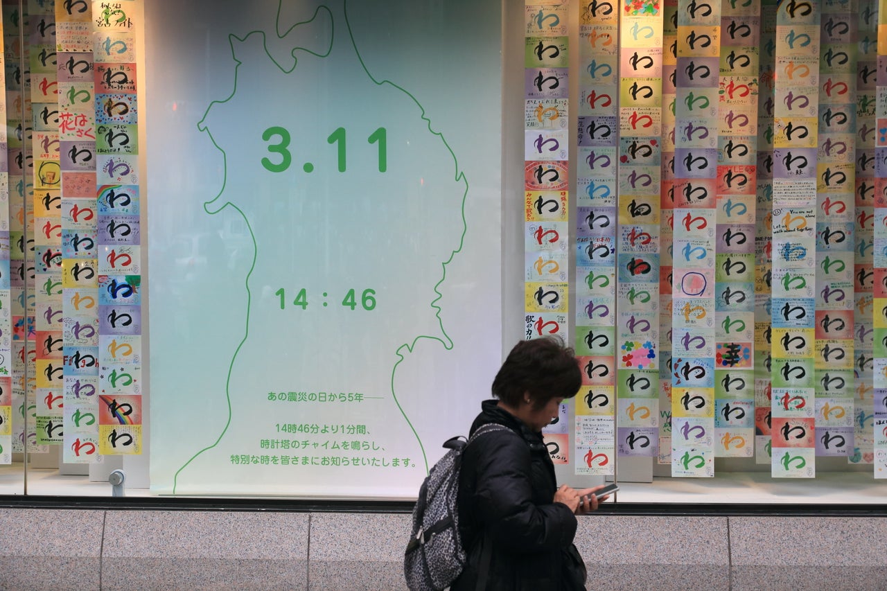 A Tokyo pedestrian walks past a display of messages mourning the victims of the earthquake.