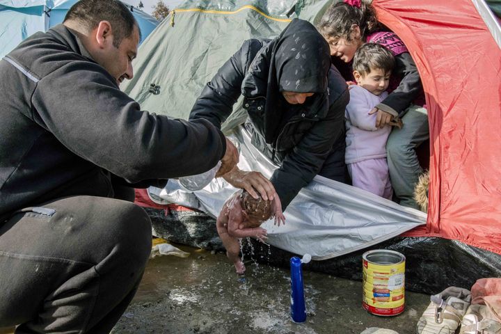 Refugees wash a new born baby as they stay in tents that they set up in the Idomeni town in Greece, near the Macedonian border on March 6, 2016