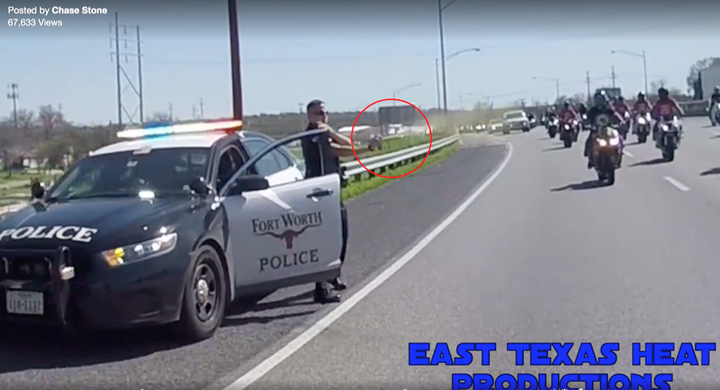 As the bikers pass, the officer appears to spray some kind of aerosol in their direction.
