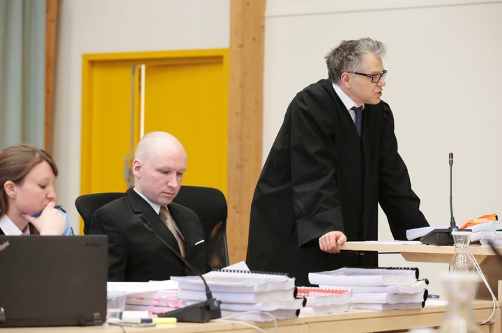 <strong>The mass killer is seated between his lawyers.</strong>