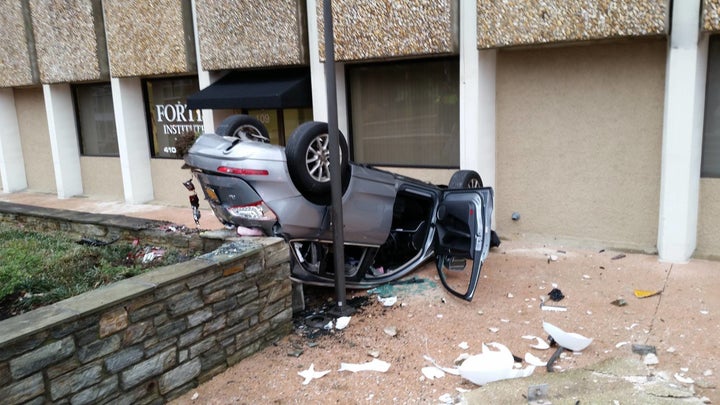 Glass and debris surround a vehicle that fell four stories from a parking garage.