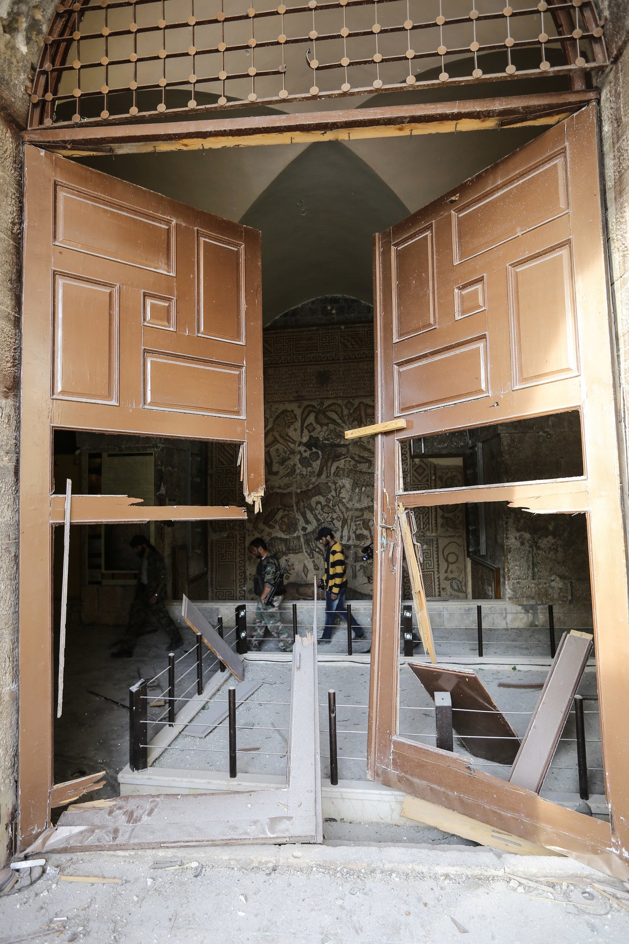 Rebel fighters walk in the grounds of al-Maraa museum