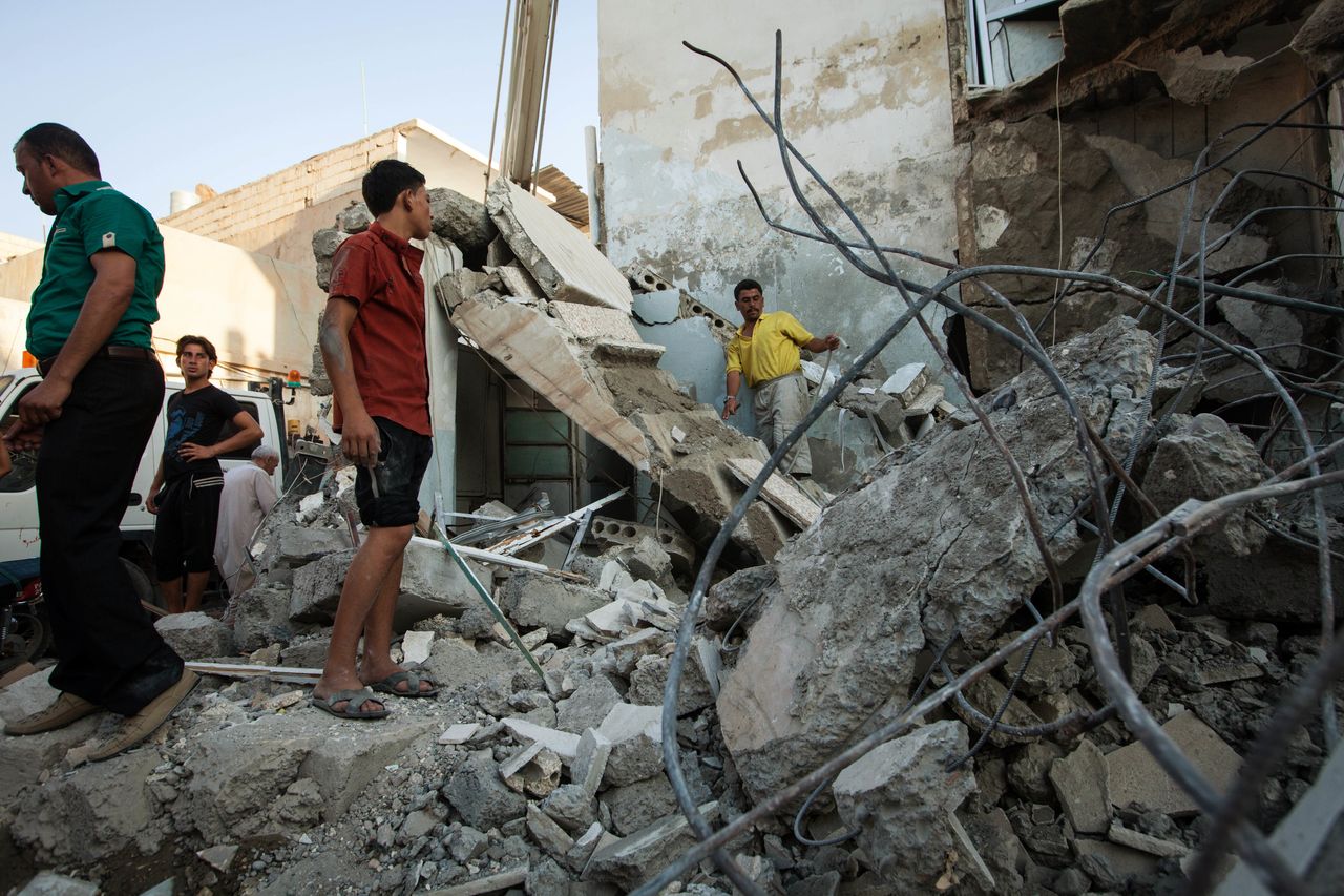 Syrians inspect debris in Raqqa after a bomb hit a building during clashes between rebel fighters and Syrian government forces on August 10, 2013