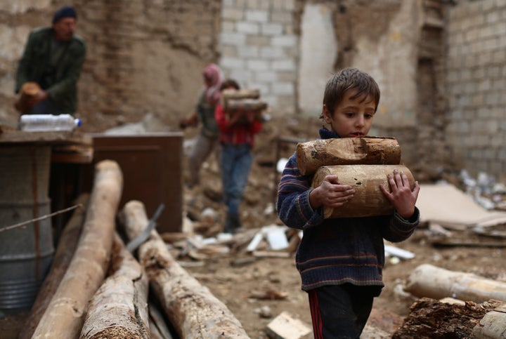 A Syrian boy carries firewood for cooking and heating in the besieged city of Douma, Syria, on November 29, 2014. Douma, has been under government siege for more than a year, with residents facing dwindling food and medical supplies.