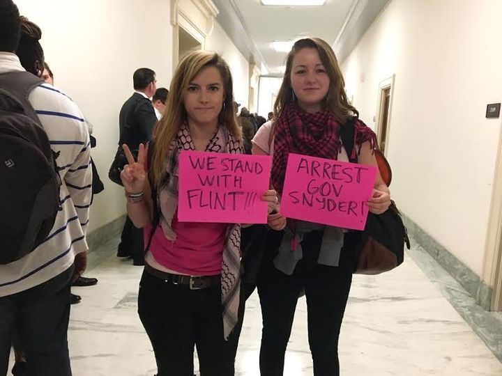 Ali McCracken, 27, and Alice Newberry, 21, of Code Pink hold signs calling for Michigan Gov. Rick Snyder's arrest.