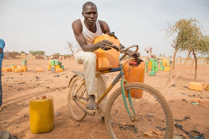 Adama Kabore rides a bike to get water in the outskirts of Ouagadougou, Burkina Faso.