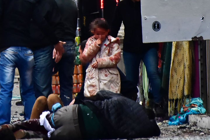 A girl cries in front of injured people in the aftermath of the blast. No group has yet claimed responsibility.