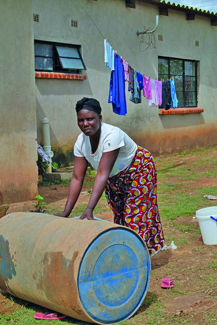 Jennifer Chikwanda rolls home a 210-liter drum of water bought from a vendor, in Lusaka, Zambia.