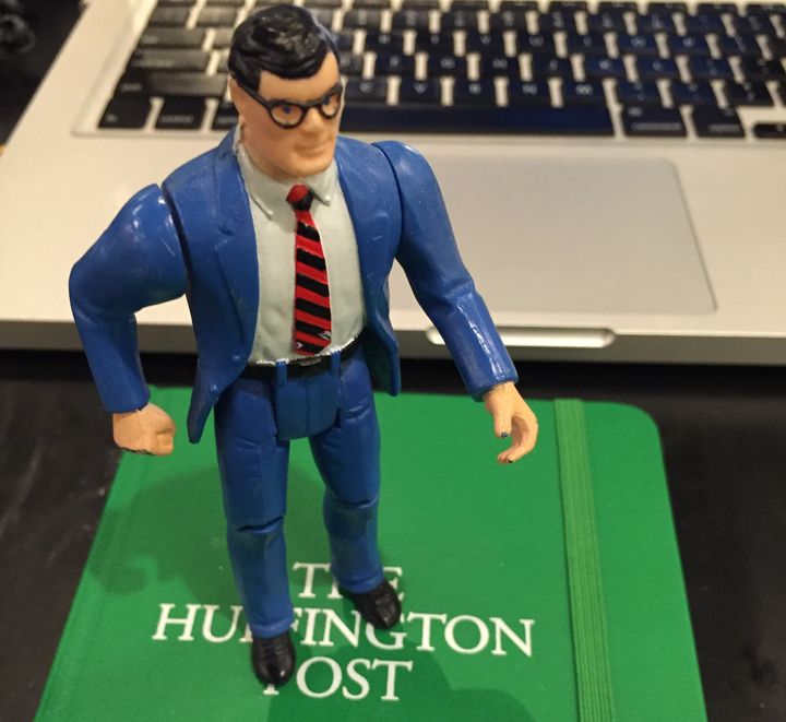 Clark Kent stands proudly atop a HuffPost notebook.