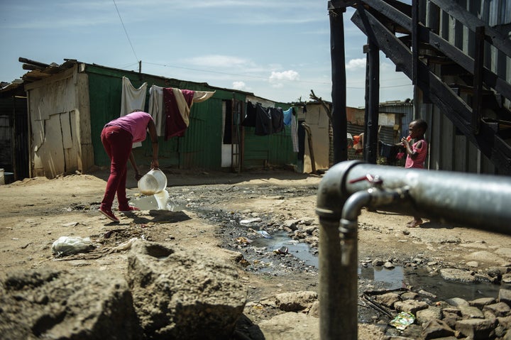 A resident of the Zandspruit informal settlement in Johannesburg empties a bucket of watsed water into a polluted stream next to a communal water tap on March 11, 2015 in Johannesburg, South Africa. 