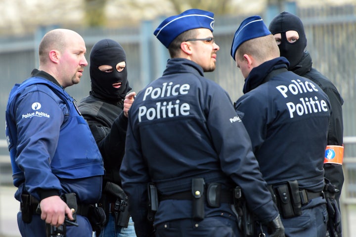 Policemen speak at a security perimeter near Maalbeek metro station on March 22, 2016, in Brussels, after a blast at this station caused deaths and injuries.