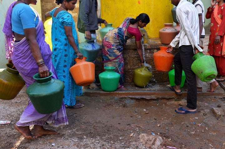This photo taken on March 18, 2015 shows residents in Bangalore collecting drinking water in plastic pots from a community ta