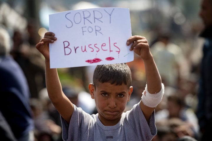 A boy holds a placard expressing sympathy for the victims of the terror attacks in Brussels during a protest at a makeshift c