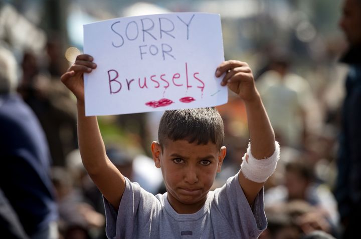 A boy holds a placard expressing sympathy for the victims of the terror attacks in Brussels during a protest at a makeshift camp at the Greek-Macedonian border near the village of Idomeni on March 22, 2016.