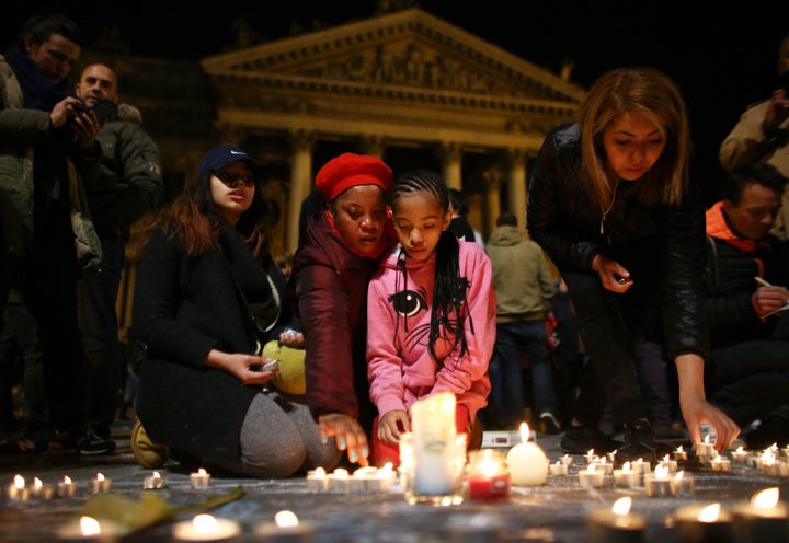 A young girl lights a candle for the attack victims at the Place de la Bourse in Brussels. Some began to sing John Lennon's Imagine, while across the city, a historic library pealed bells in a gesture of solidarity and hope.