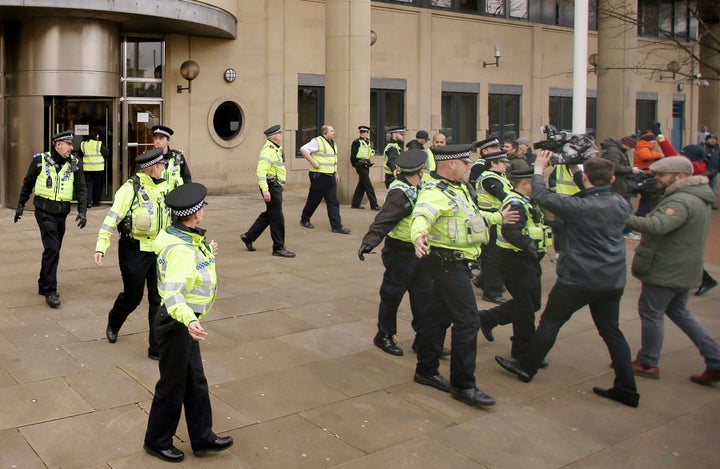 Police officers shepherd the media outside court after Johnson ran into