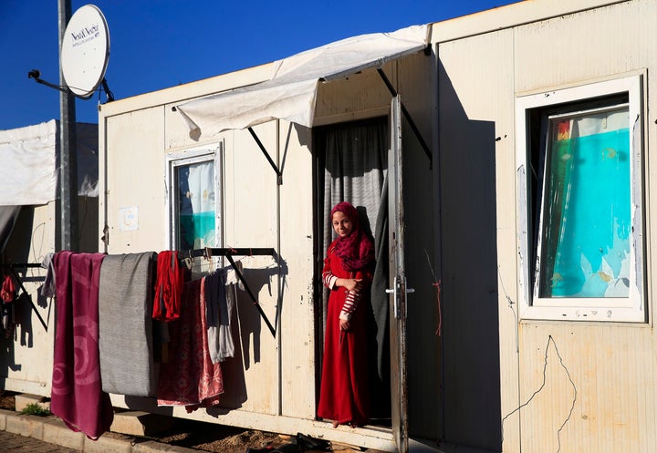 A Syrian refugee woman stands at the entrance of the container where her family is living, at the Oncupinar camp for Syrian refugees next to a border crossing in southeastern Turkey on Thursday, March 17, 2016.