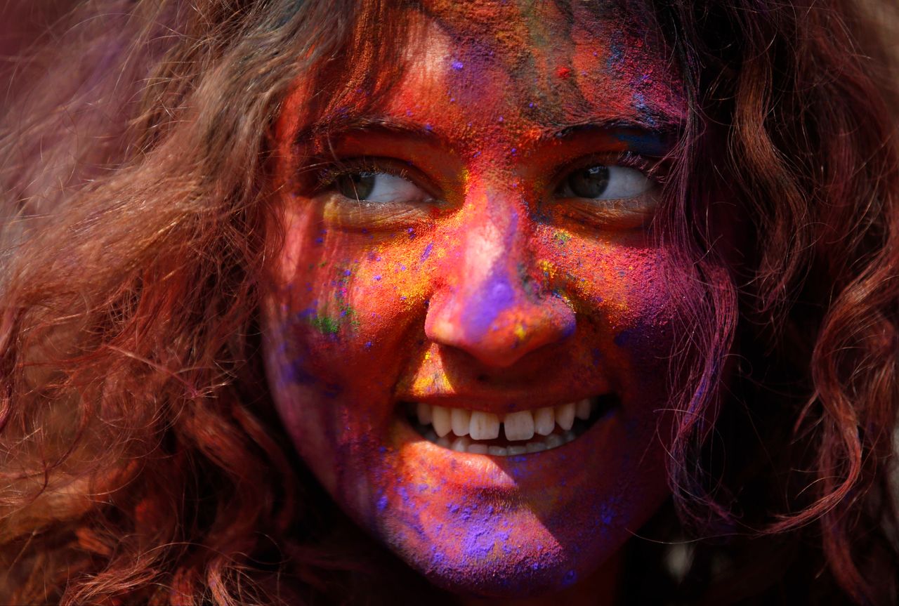 A woman with colored powder smeared on her face smiles as she celebrates Holi, the Festival of Colours, in Kathmandu, Nepal.