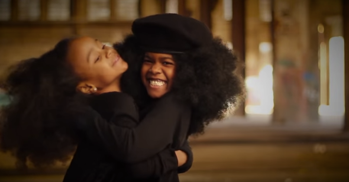 Two young black girls embrace each other in a warm hug in Johnson's video. 