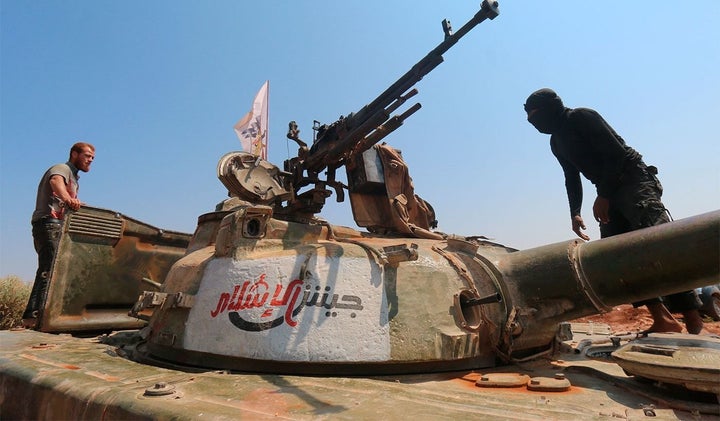 Rebel forces from Jaish al-Islam stand on a tank near a frontline in Syria last August. The group's leader was killed in December last year in a government air strike.