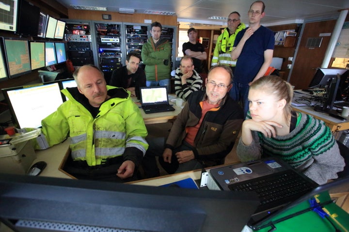 Peter Linke (center), scientists and engineers gather around video monitors in the ship's instrument room to monitor the descent and release of a seafloor lander.