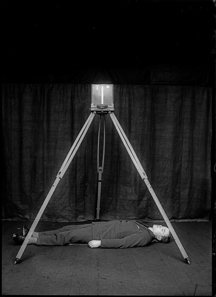Demonstrative image of Bertillon's forensic photographic approach, with a body simulating a corpse and the camera in position. Used as teaching material for courses and conferences.