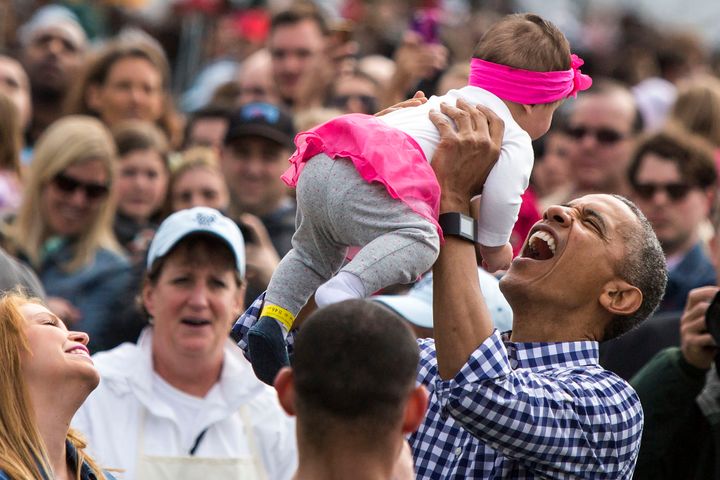 President Barack Obama lifts a young girl in the air during the White House Easter Egg Roll on the South Lawn of the White House on Monday.