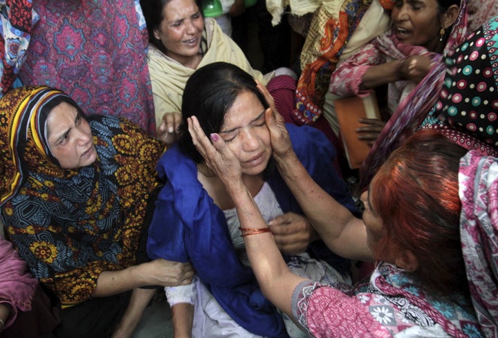 Family members comfort a woman mourns the death of a relative, who was killed in a blast outside a public park on Sunday, dur