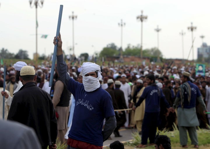 A man holds a stick while taking part in a sit in protest against the execution of Mumtaz Qadri outside the Parliament buildi