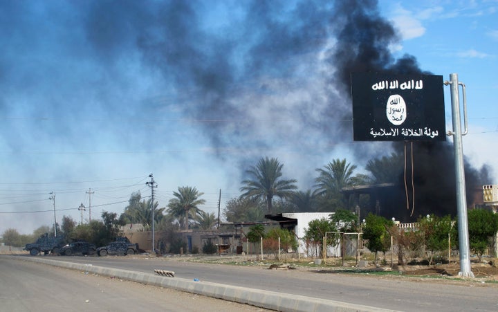 Smoke rises behind an Islamic State flag in Saadiya, Iraq.