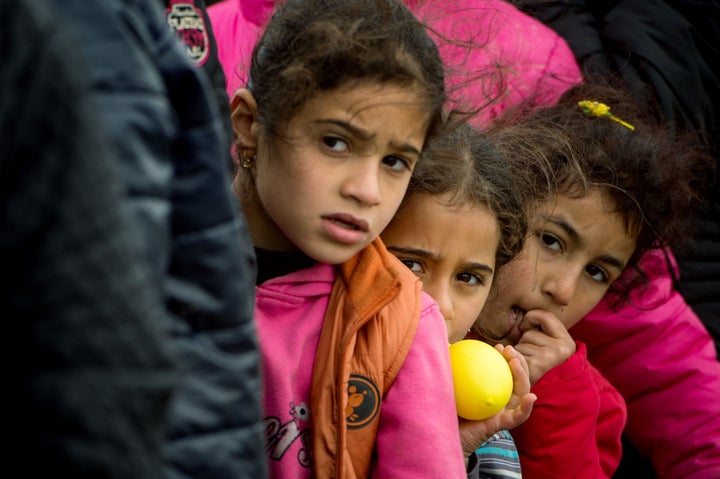 Children queue up for food distributed at a makeshift camp occupied by migrants and refugees at the Greek-Macedonian border near the village of Idomeni on March 24, 2016.