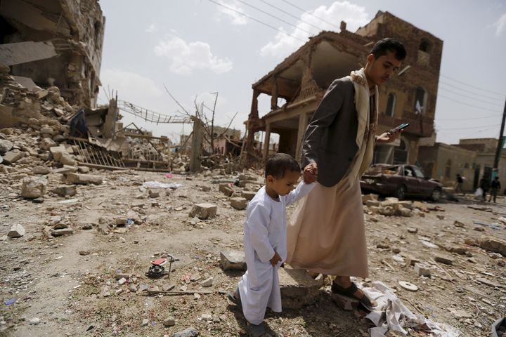 A man and a boy walk at a site hit by a Saudi-led air strike in Yemen's capital, Sanaa, on July 3, 2015. In the last year, more than 900 children in Yemen were killed and more than 1,300 were injured, a new report from UNICEF says.