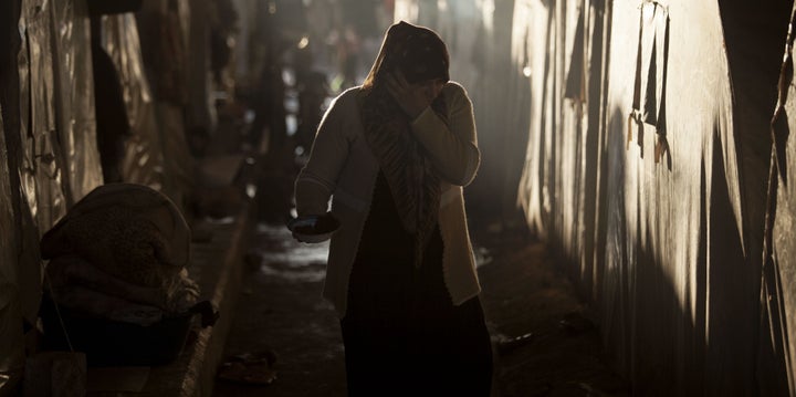 A Syrian refugee woman is seen between a line of tents in a refugee camp near Azaz, north of Aleppo province, on Sunday, Feb